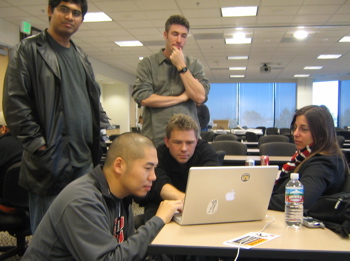 A Hack Day team gathered around a laptop, thinking through their hack