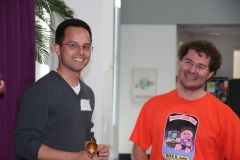 Two smiling hackers at Yahoo! Hack Day, one holding a small bell