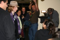 Beck, in a hat and scarf, checking out the hacks as a camera crew films