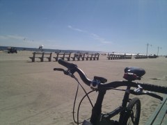 My bike parked on the beach at Jacob Riis Park, with the boardwalk benches behind it
